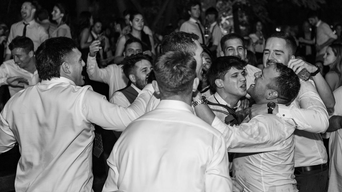 Group of men in formal attire celebrating and dancing at a party in Mendoza, Argentina.